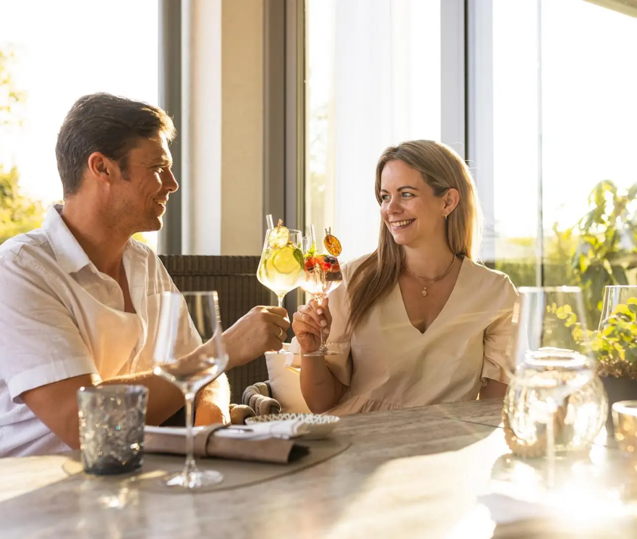 Glückliches Paar stößt mit erfrischenden Cocktails auf der Terrasse des VILA VITA Pannonia an.