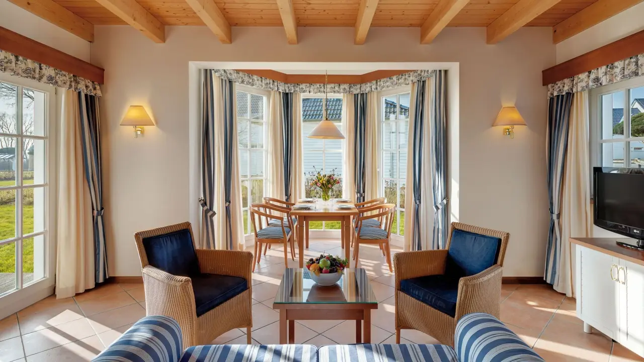 Helles Wohn- und Esszimmer einer Suite im Precise Resort Schwielowsee mit maritimer Einrichtung und Blick auf den Garten.