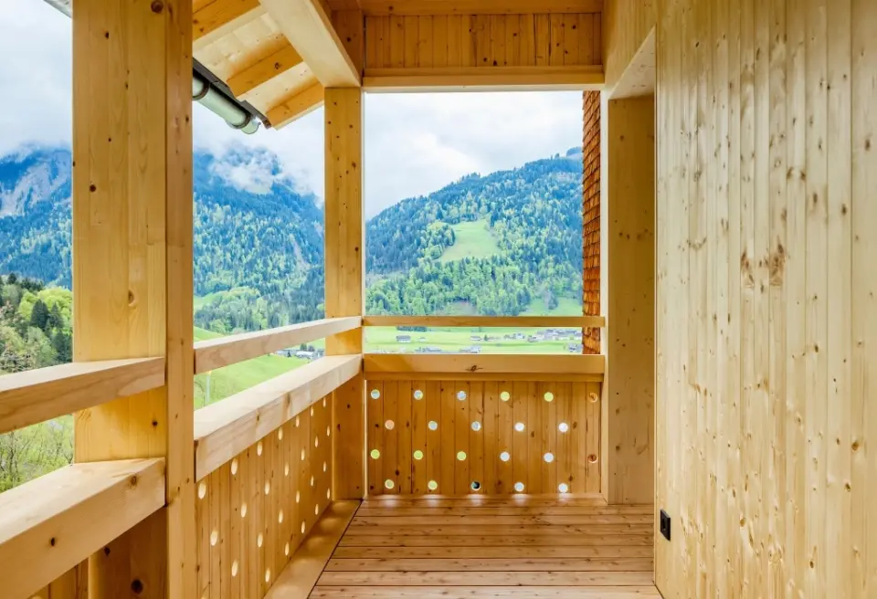 Balkon aus hellem Holz mit Panoramablick auf grüne Berge und das Tal im Hotel Am Holand.