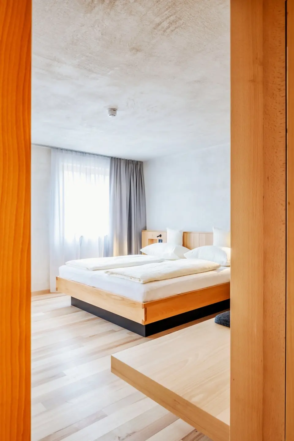 Modernes Hotelzimmer im Hotel Am Holand mit hellem Holzdesign, Doppelbett und viel Tageslicht.