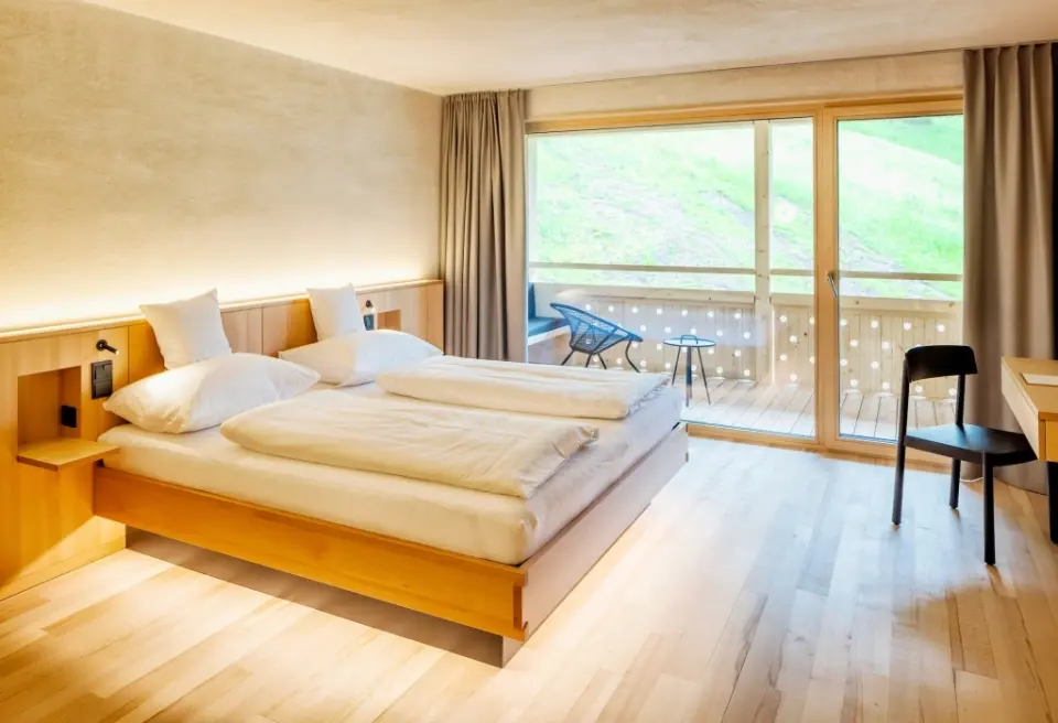 Helles Doppelzimmer im Hotel Am Holand mit Holzboden, Balkon und Blick ins Grüne.