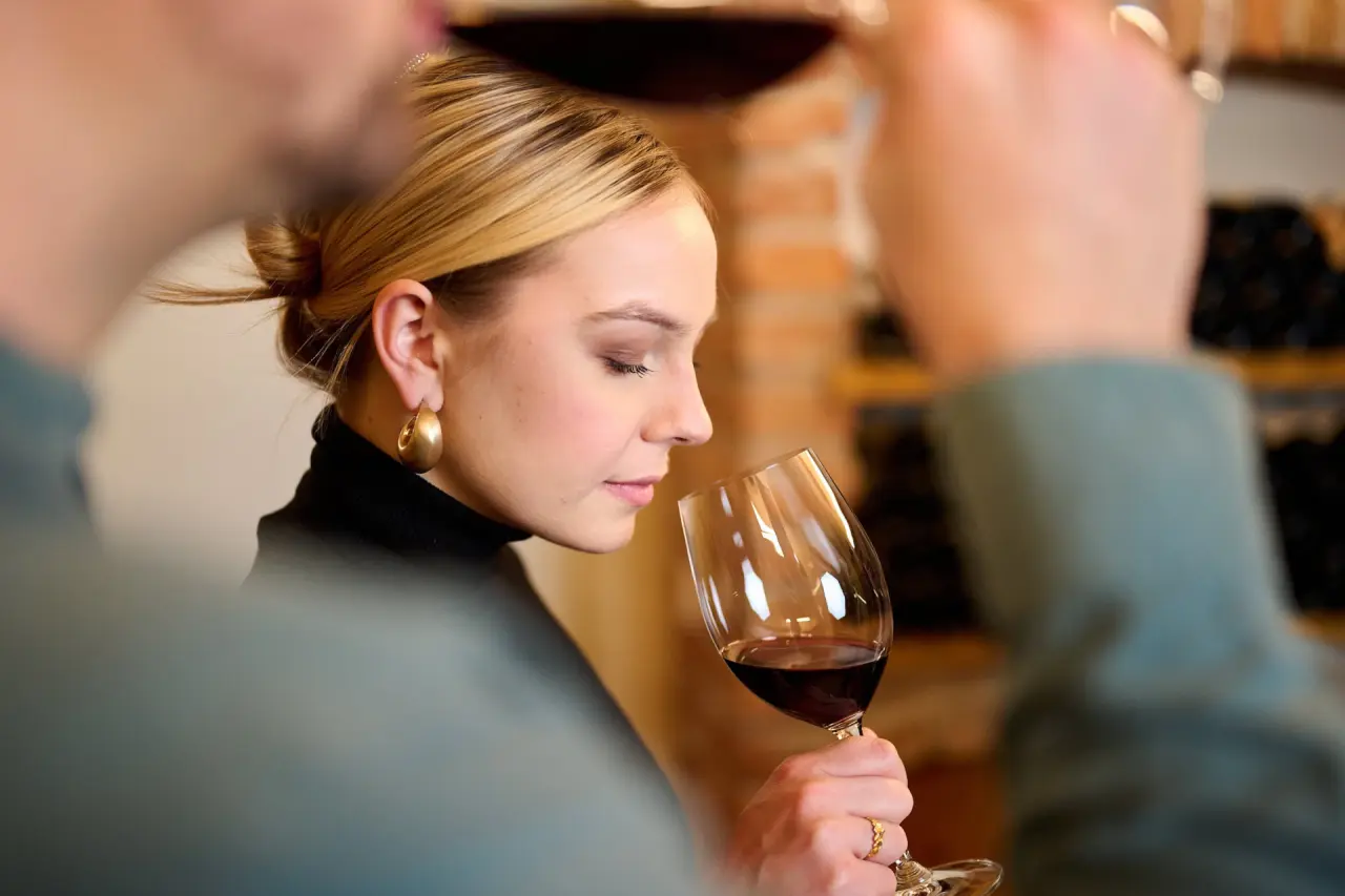 Frau genießt Rotwein bei einer Weinprobe im Landhotel Schermer. Einblick in das kulinarische Angebot des Hotels.