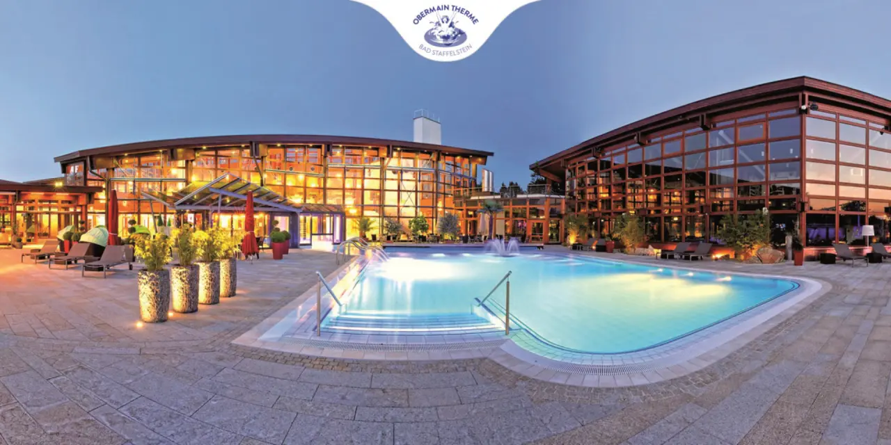Beleuchteter Aussenpool und moderne Thermen-Architektur des Best Western Plus Kurhotel an der Obermaintherme bei Dämmerung.