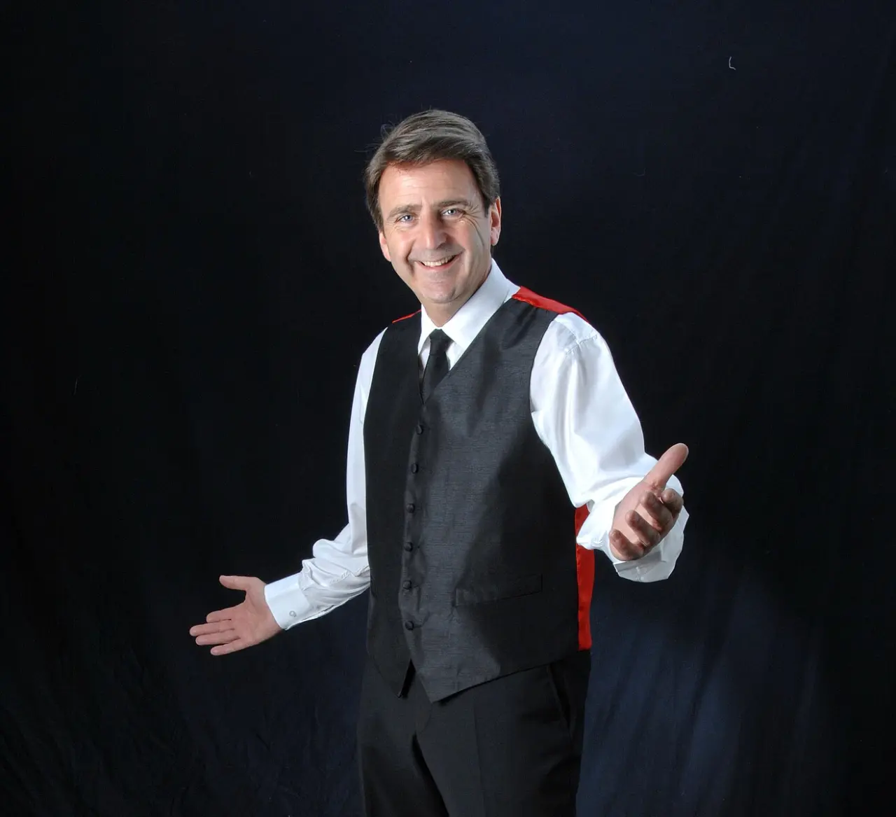 Porträt eines freundlichen Mannes im Anzug mit rotem Detail vor schwarzem Hintergrund im Parkhotel Weiskirchen.