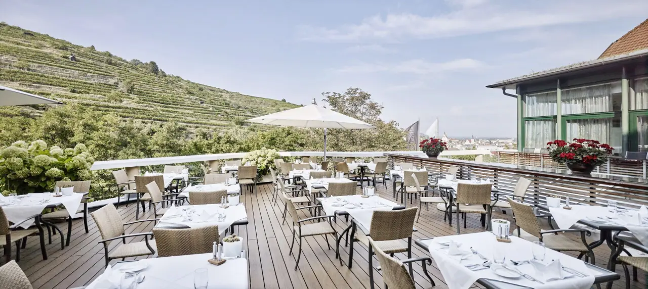 Sonnige Restaurantterrasse mit Blick auf die Weinberge und die Stadt Krems im Steigenberger Hotel and Spa Krems.
