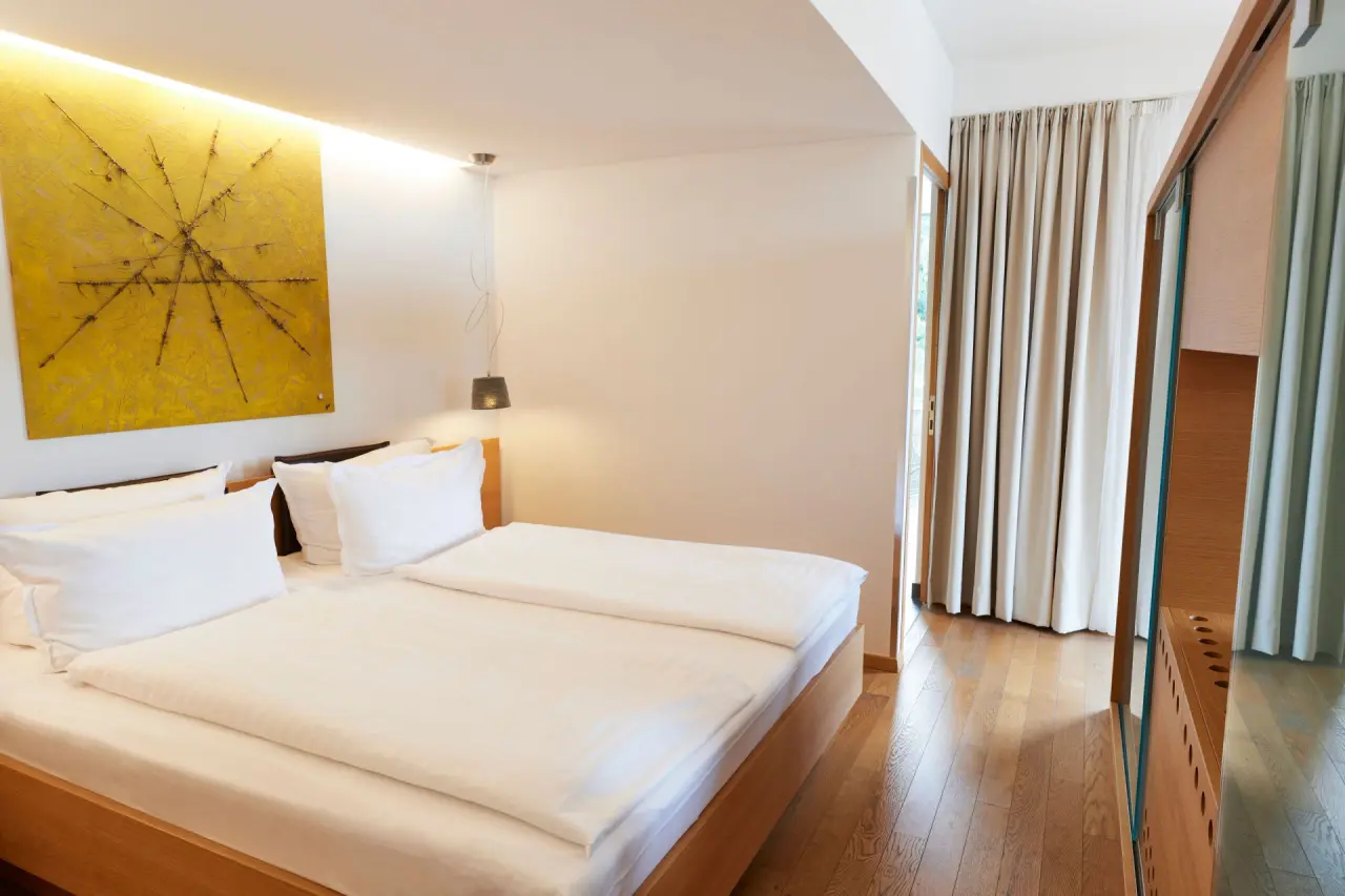 Helles, modernes Doppelzimmer mit Holzboden und Balkonzugang im Steigenberger Hotel and Spa Krems.