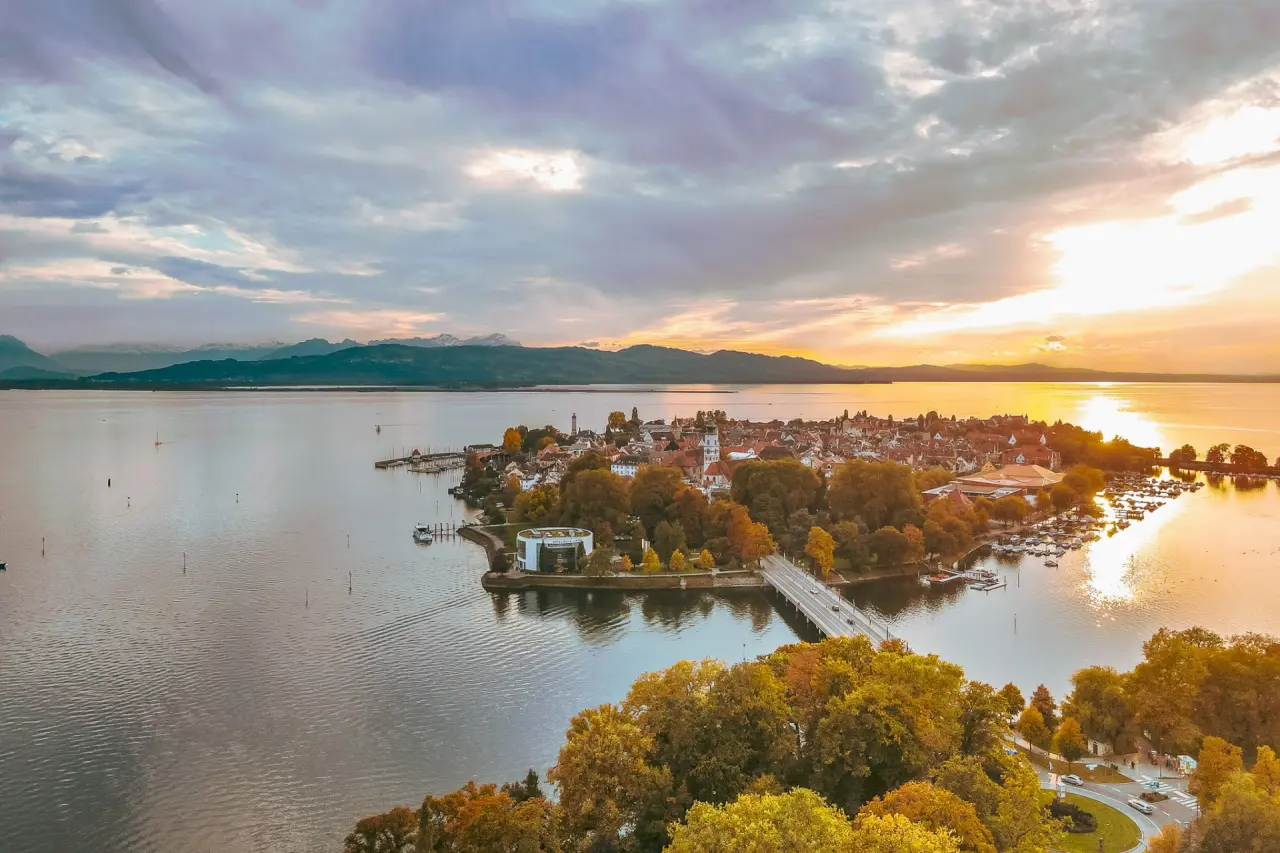 Malerische Luftaufnahme der Insel Lindau am Bodensee mit Alpenpanorama bei Sonnenuntergang, Hotel Helvetia.