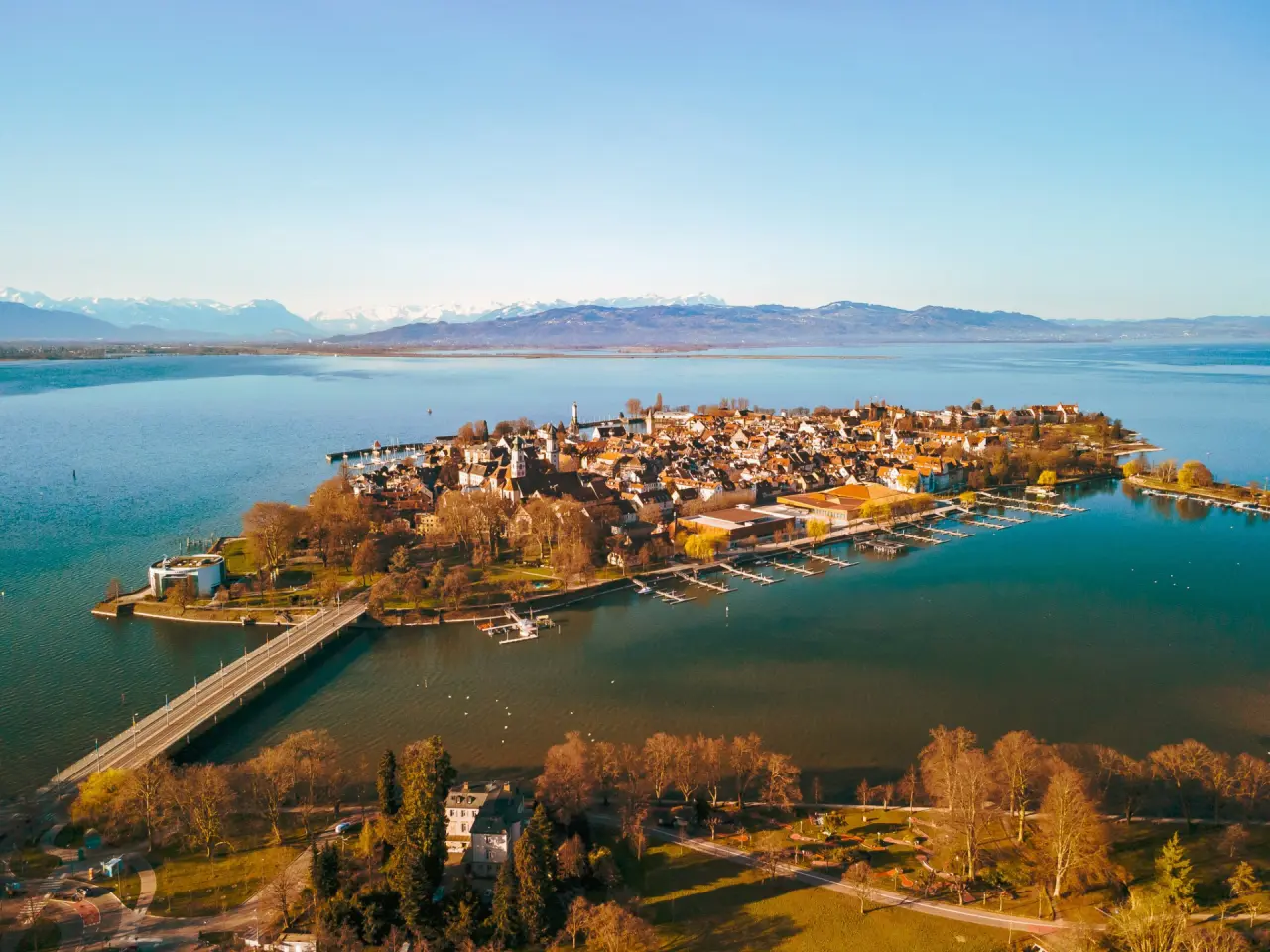 Luftbild der Inselstadt Lindau im Bodensee mit Alpenpanorama im Hintergrund, ideal für Wellnessgäste des Hotel Helvetia.