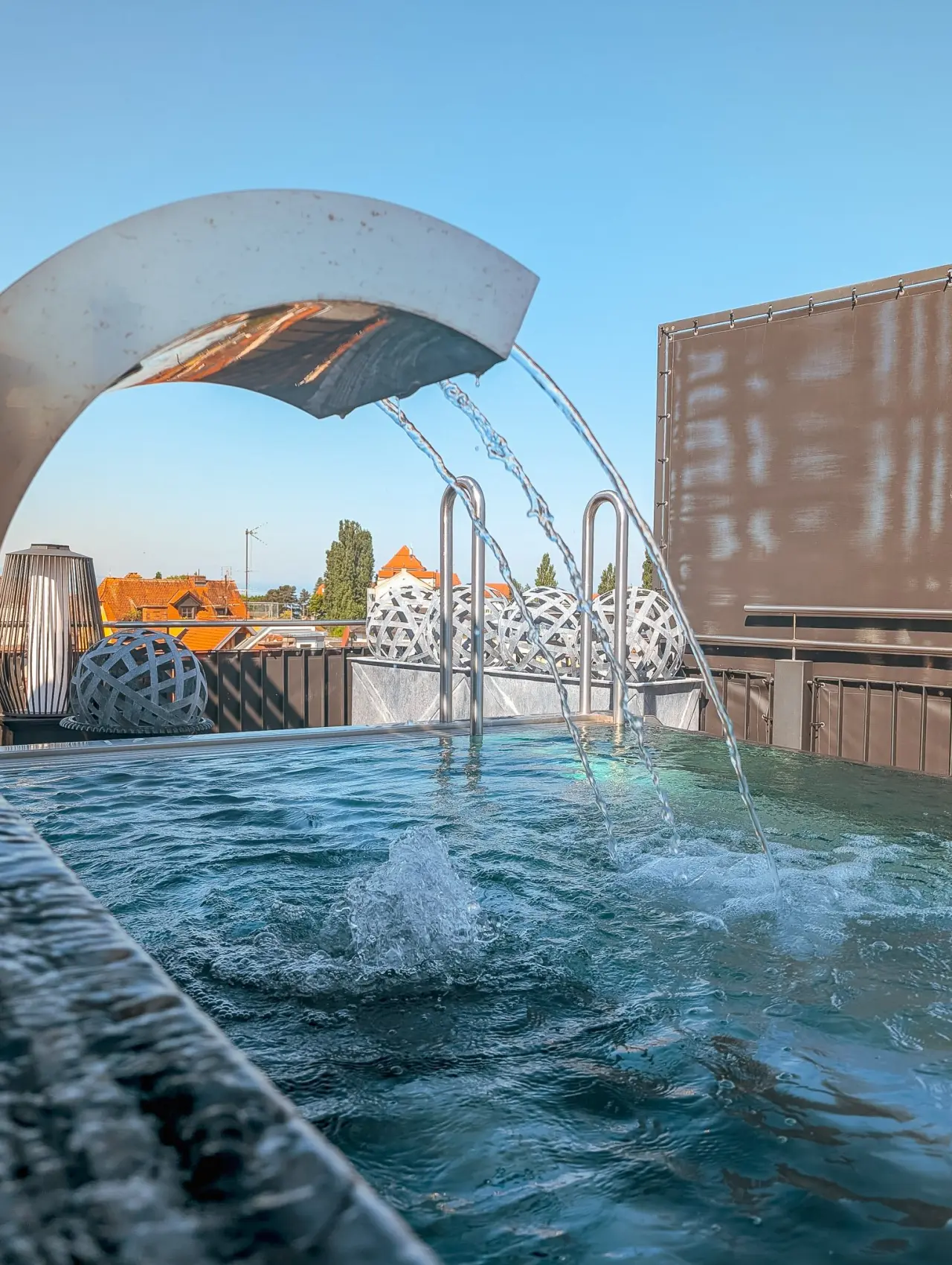 Rooftop-Pool mit Wasserspiel und Stadtblick im Hotel Helvetia bei Sonnenlicht