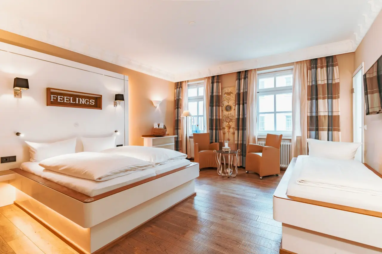 Einladendes Doppelzimmer mit modernem Bett, Holzboden und gemütlichem Sitzbereich im Hotel Helvetia.