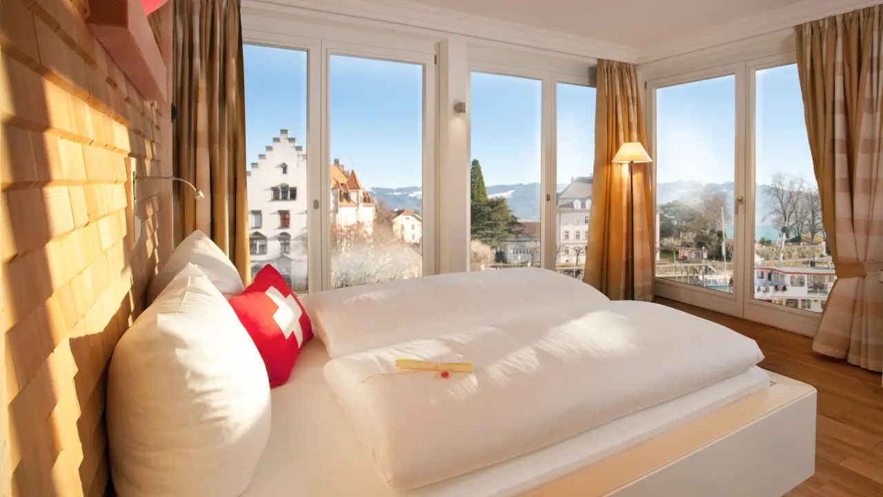 Komfortables Hotelzimmer im Hotel Helvetia mit Seeblick, Holzwand und gemütlichem Bett. Ideal für entspannte Aufenthalte.