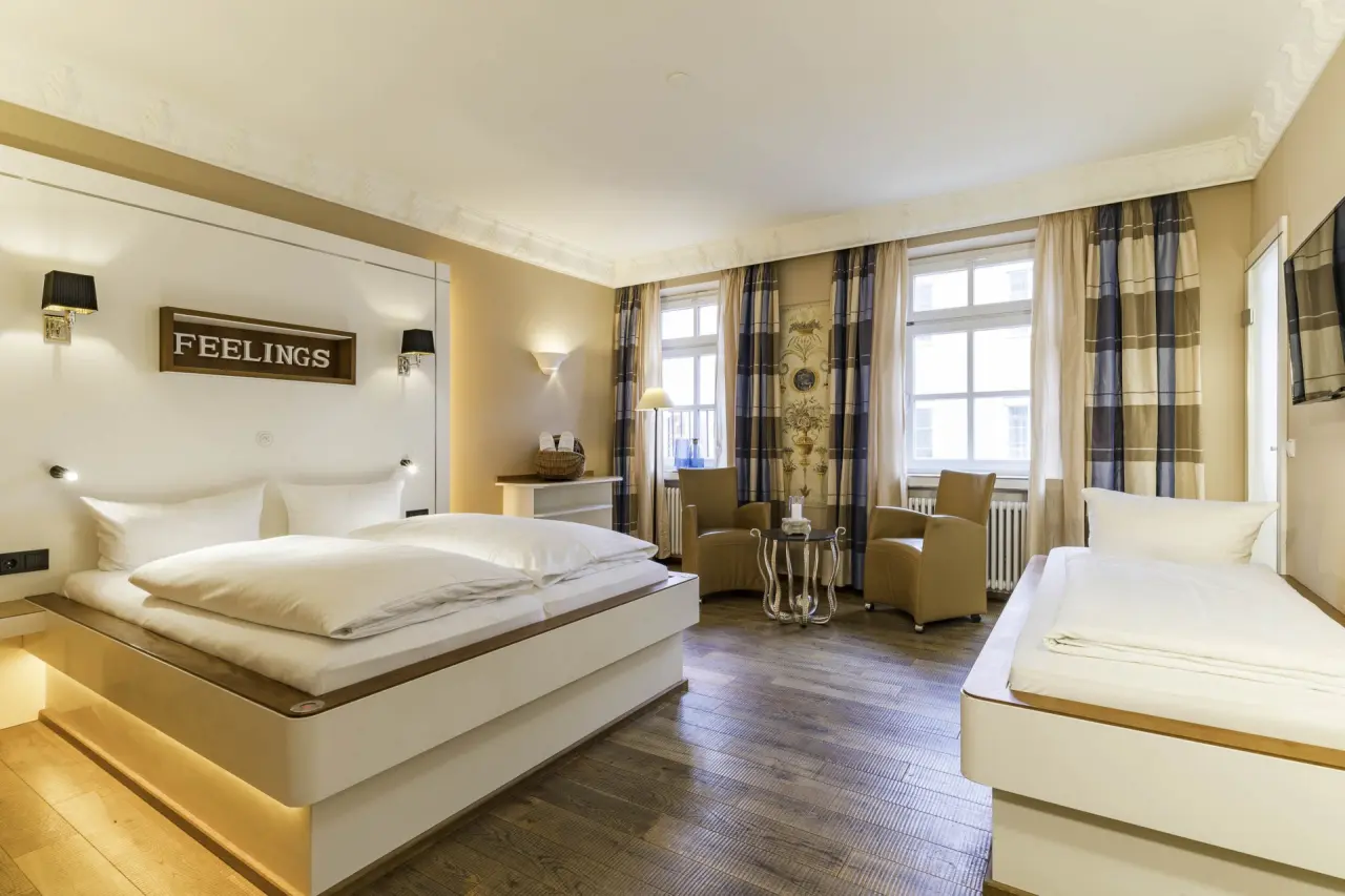 Geräumiges Doppelzimmer mit zusätzlichem Einzelbett und Sitzbereich im Hotel Helvetia.