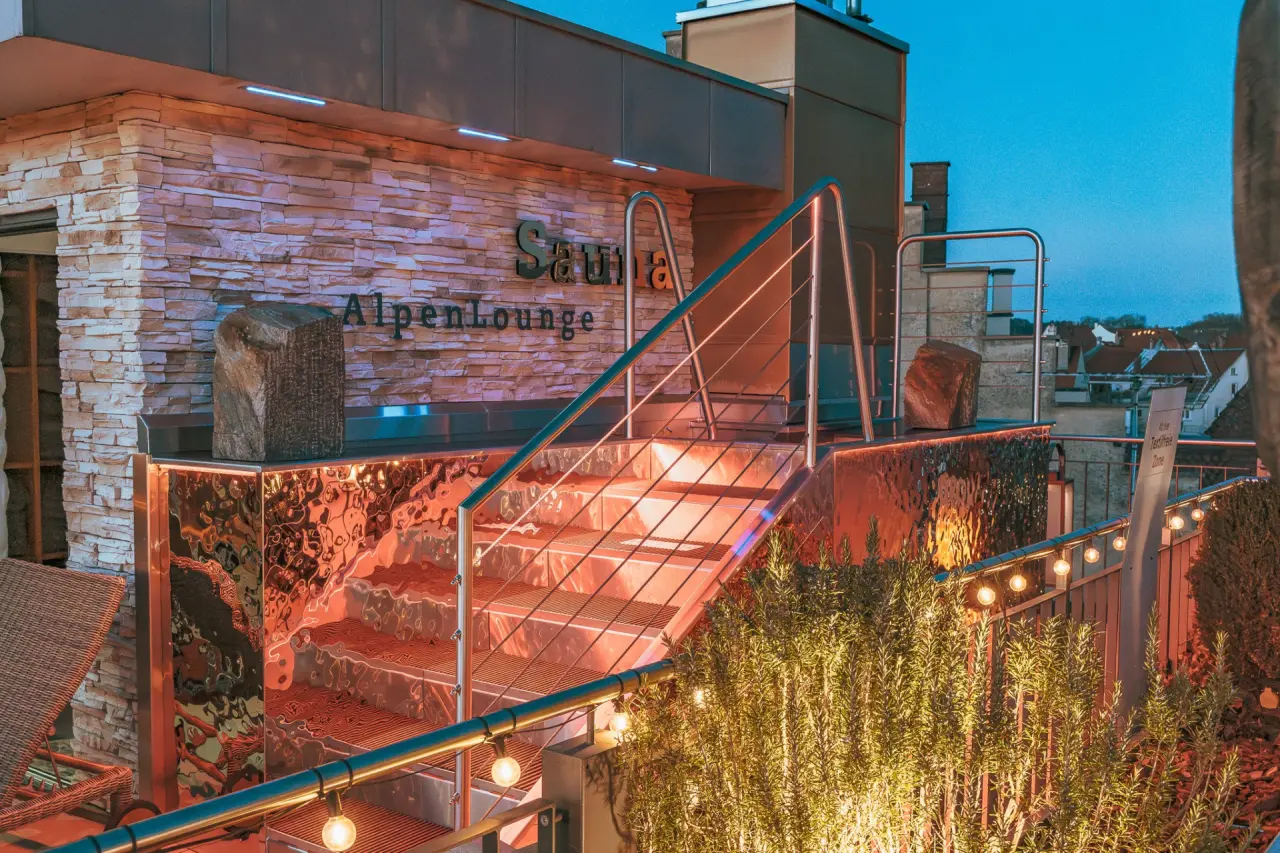 Beleuchteter Eingang zur Sauna AlpenLounge auf der Dachterrasse des Hotel Helvetia bei Nacht.