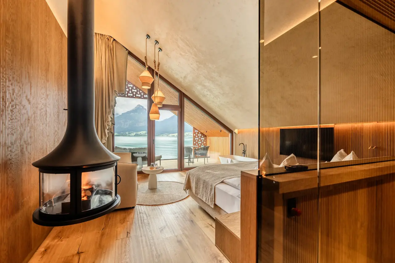 Luxuriöses Hotelzimmer im Hotel Seevilla Wolfgangsee mit Kamin, freistehender Badewanne und Panoramablick auf den See und die Berge.