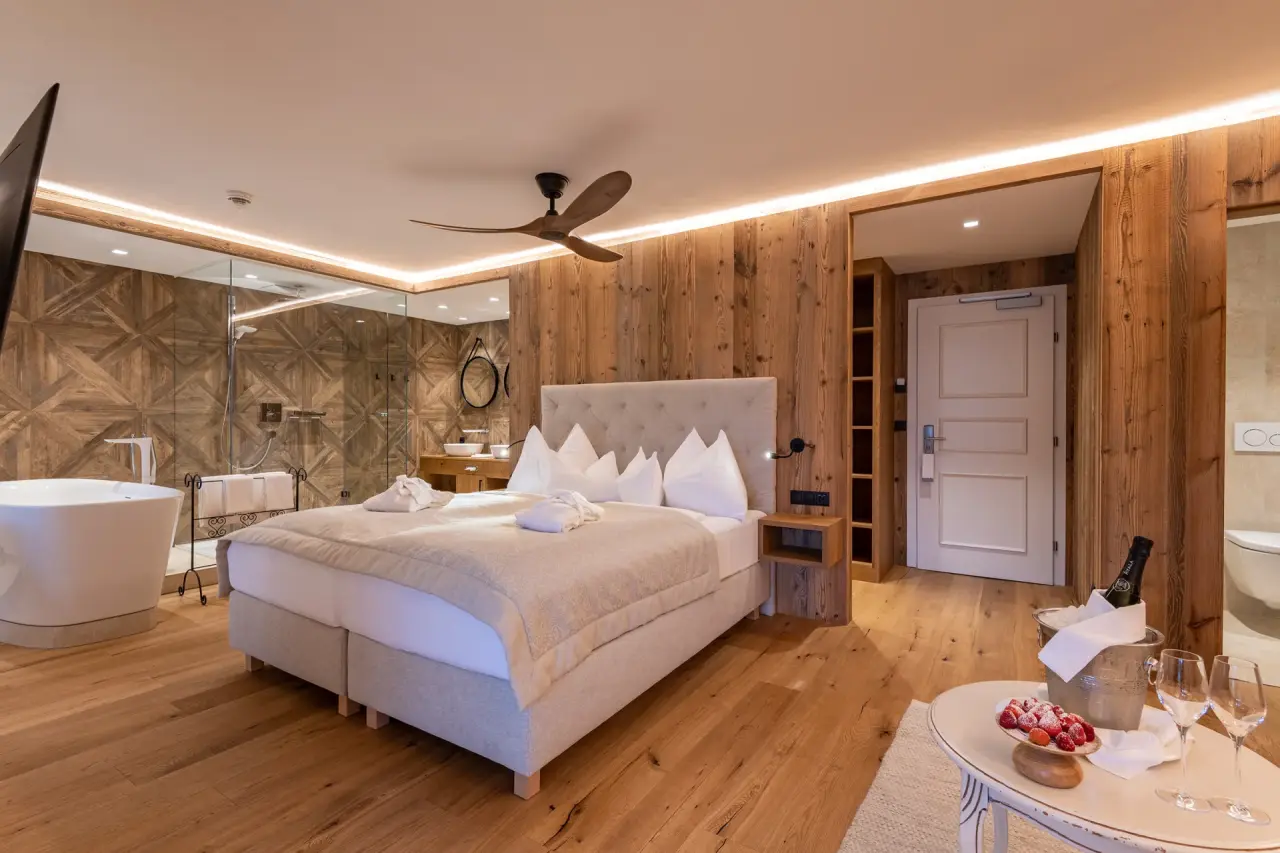 Luxuriöses Hotelzimmer im Hotel Seevilla Wolfgangsee mit Holzelementen, freistehender Badewanne und offener Dusche.