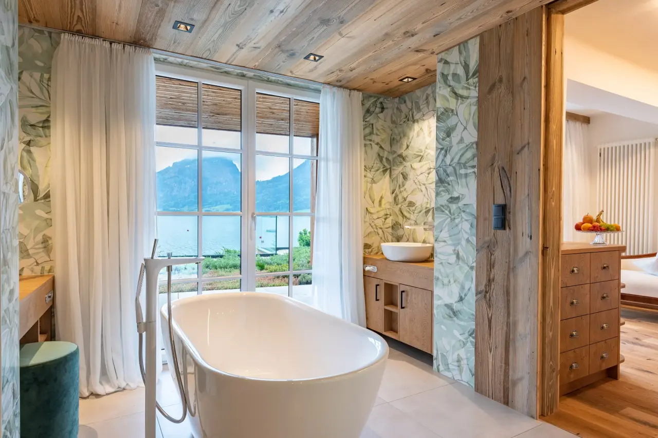 Luxuriöses Badezimmer mit freistehender Badewanne und Panoramablick auf den Wolfgangsee im Hotel Seevilla Wolfgangsee.