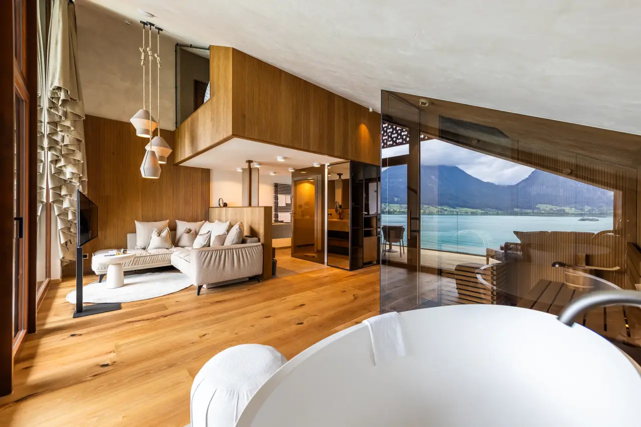 Luxuriöses Hotelzimmer im Hotel Seevilla Wolfgangsee mit freistehender Badewanne und Panoramablick auf den Wolfgangsee und die Berge.