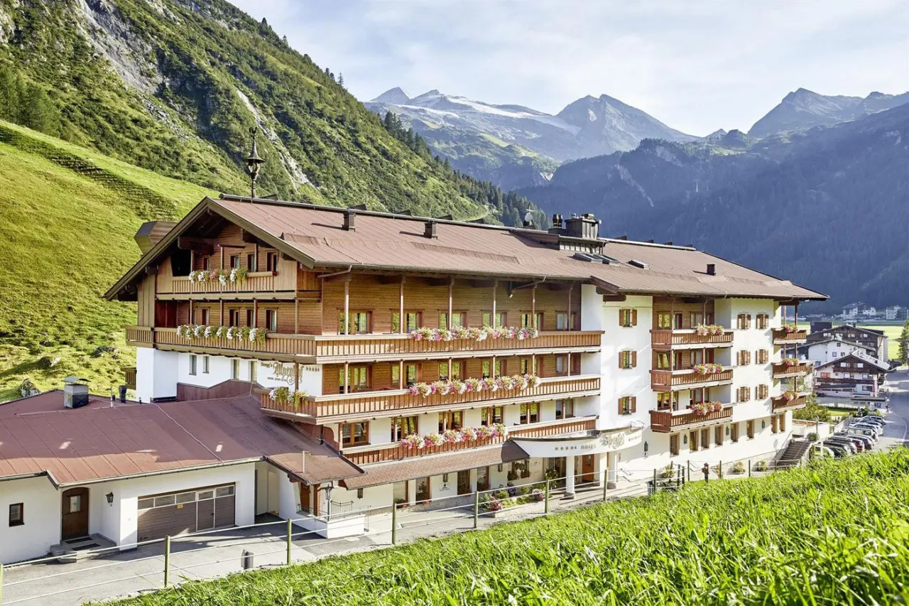 Traditionelles Hotel Alpenhof in den Alpen mit blühenden Balkonen und beeindruckendem Bergpanorama.