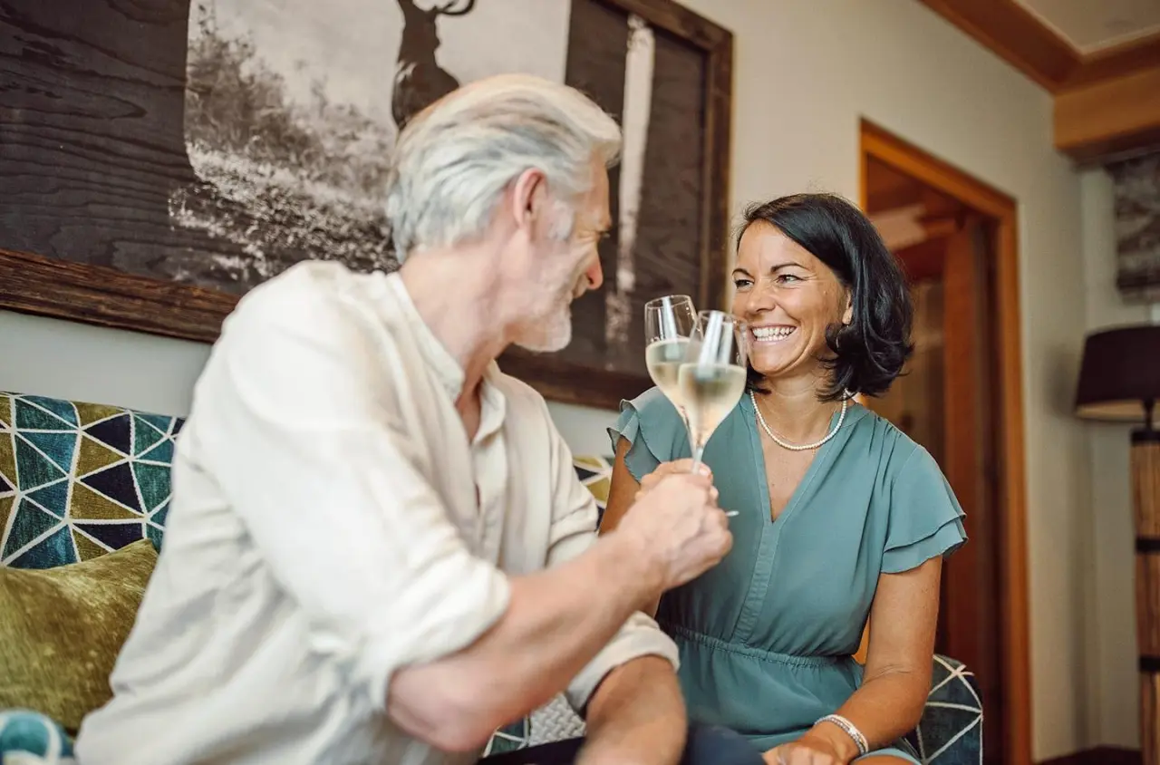 Lachendes Paar genießt Sekt in der stilvollen Lounge des Hotel Waldfrieden.