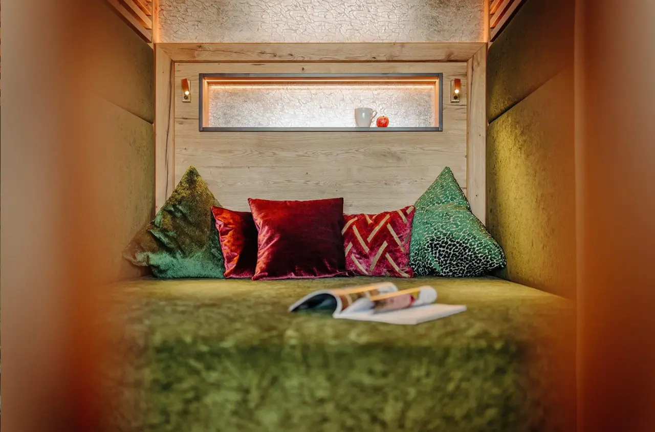 Gemütliche Leseecke mit Samtkissen und warmem Licht im Ruhebereich des Hotel Waldfrieden.