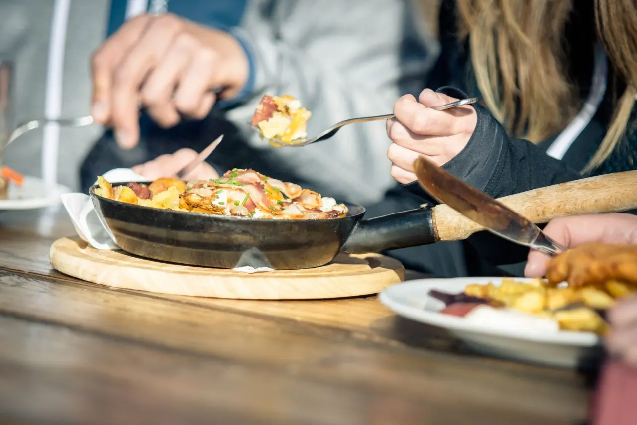 Herzhaftes Pfannengericht mit Speck und Kartoffeln, von Gästen im Restaurant des Hotel Alpenland genossen.