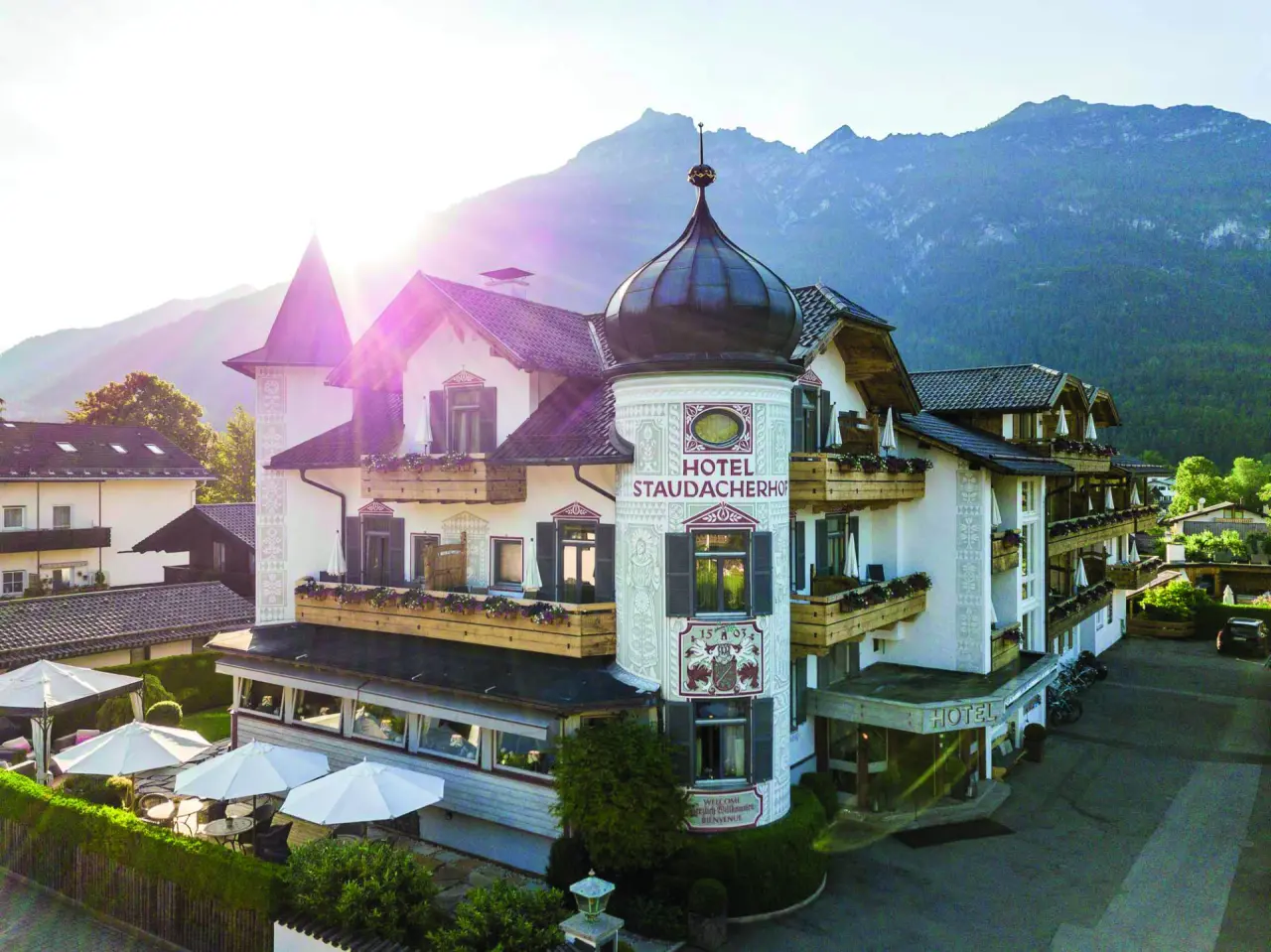 Traditionelle Aussenansicht des Hotel Staudacherhof mit charakteristischer Architektur und Bergpanorama im warmen Sonnenlicht.