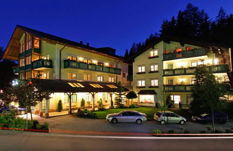 Nachtansicht des Hotel Annelies mit beleuchteten Balkonen und traditioneller Architektur vor dunklem Waldhintergrund.