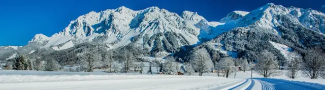 Majestätische Winterlandschaft mit verschneiten Bergen und präparierter Langlaufloipe beim Hotel Annelies.