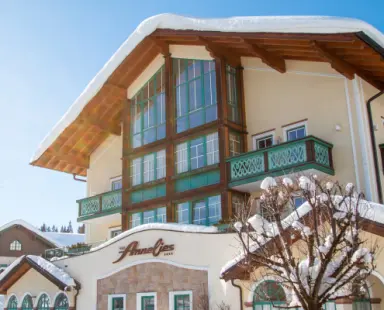 Verschneite Aussenansicht des Hotel Annelies im Winter mit traditioneller Alpenarchitektur und blauem Himmel.