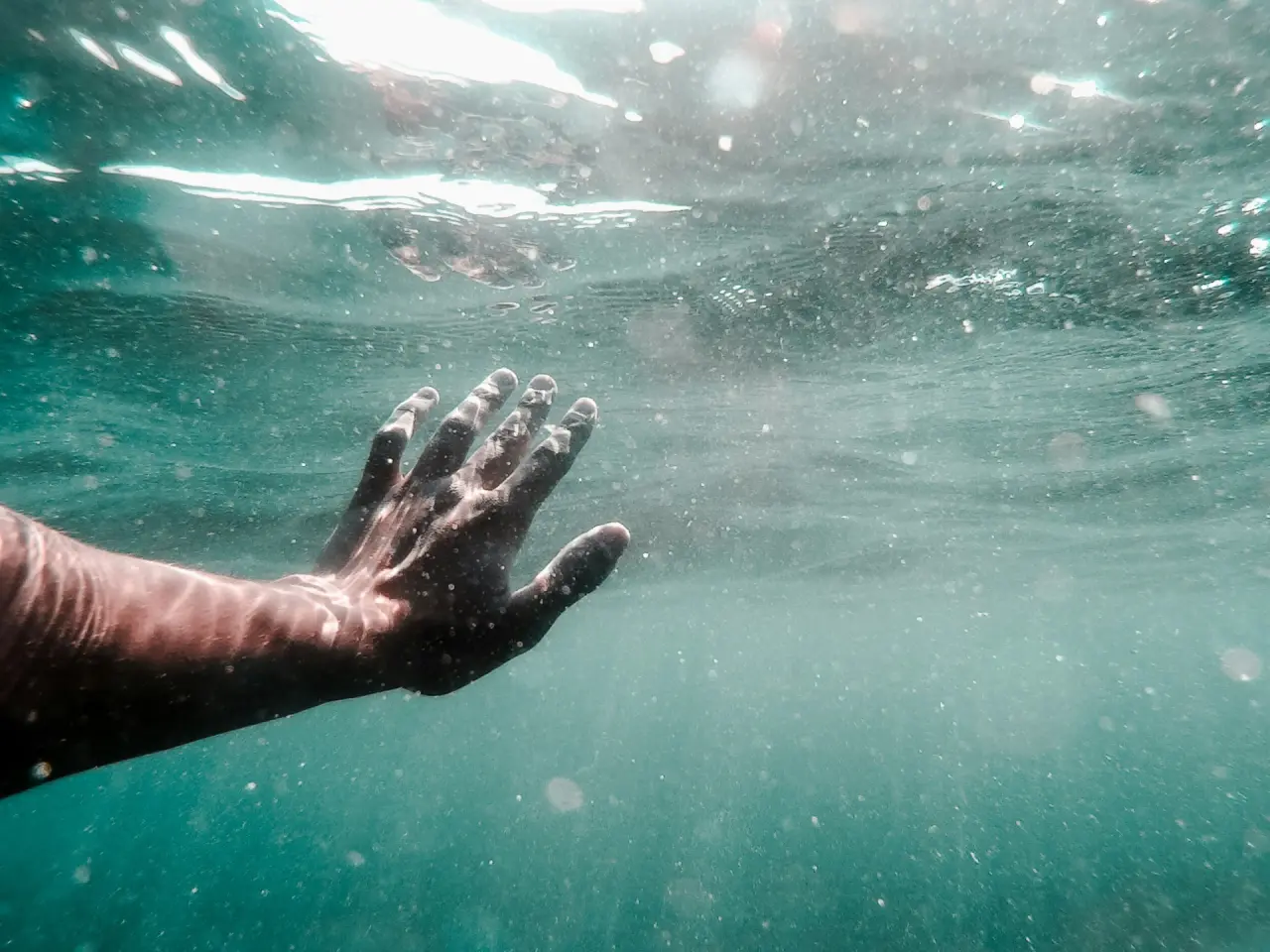 Unterwasseraufnahme einer Hand im See des Hotel Solthus am See. Symbolisiert Ruhe und Erfrischung im kühlen Nass.