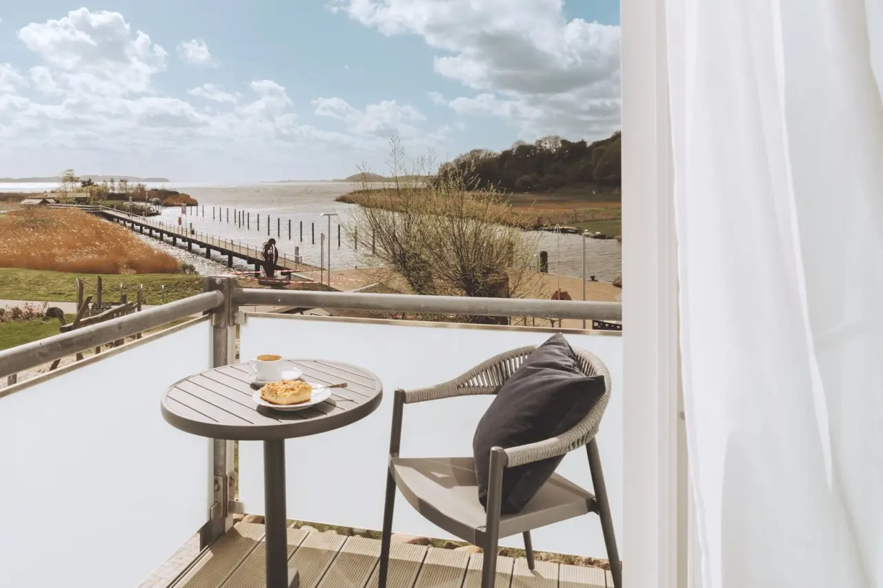 Balkon mit Seeblick und Kaffee im Hotel Solthus am See. Gemütlicher Sitzbereich mit Blick auf den See und Steg.