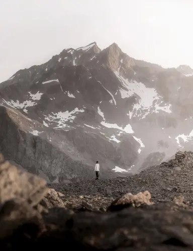 Person blickt auf majestätische, schneebedeckte Berge in nebliger Landschaft, nahe Hotel Regina.