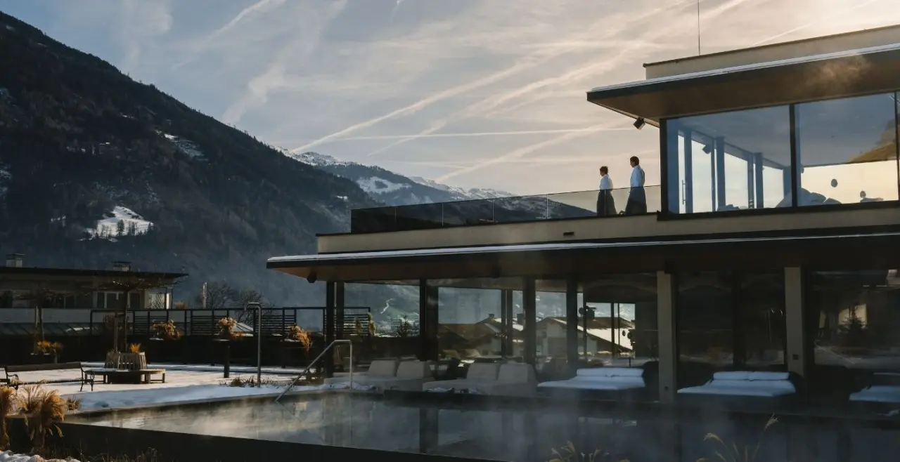 Winterliche Aussenansicht des Sport- und Wellnesshotel Held****s mit beheiztem Aussenpool und Bergblick.