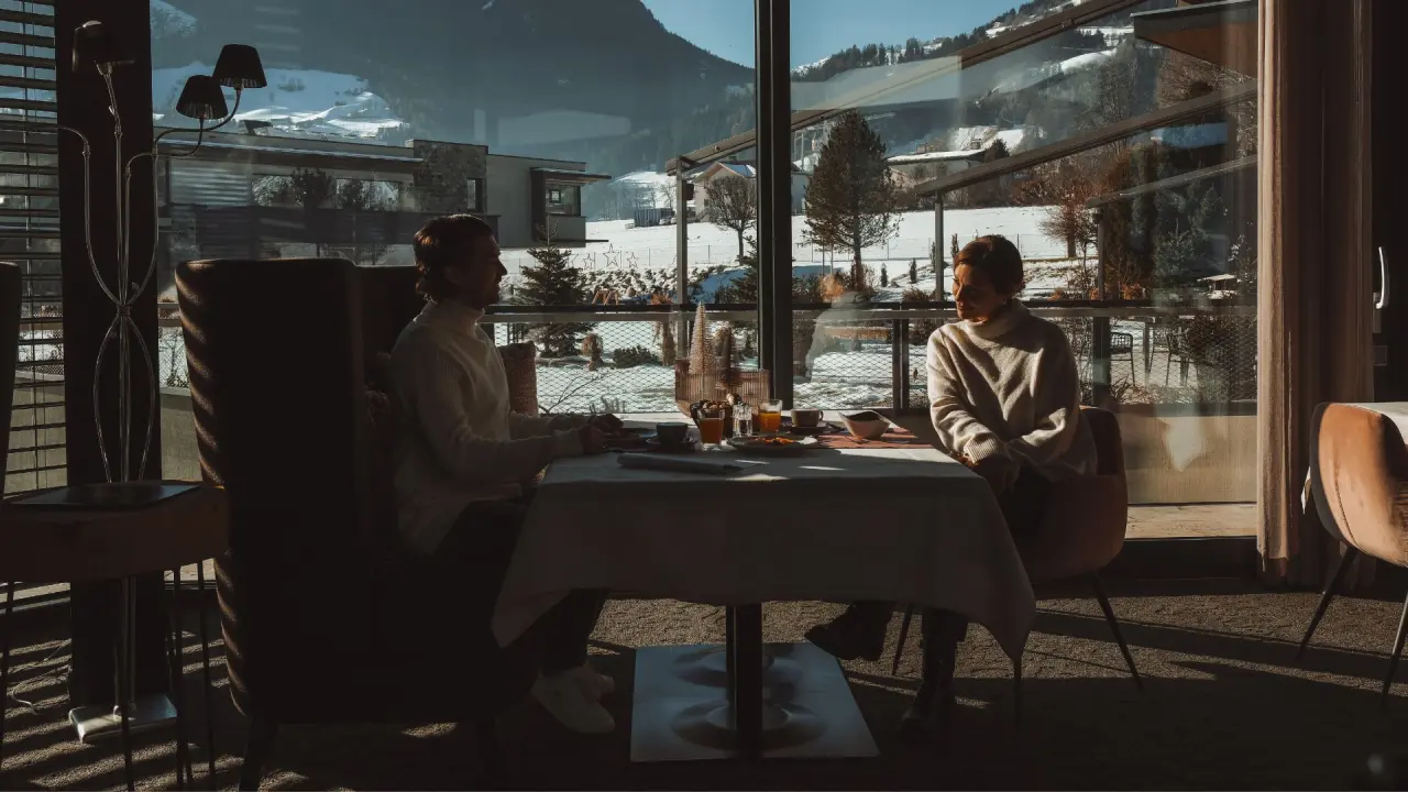 Gäste beim Frühstück mit Panoramablick auf die verschneite Bergwelt im Sport- und Wellnesshotel Held****s.