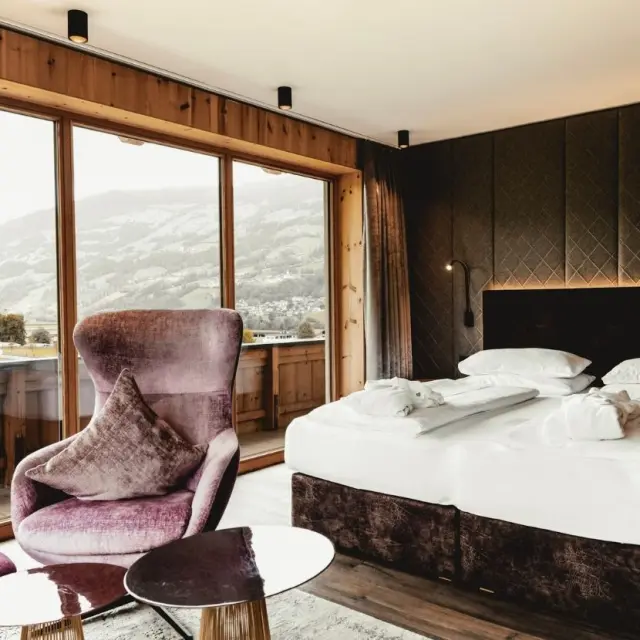 Komfortables Hotelzimmer mit Bergblick, gemütlichem Sessel und Bademänteln im Sport- und Wellnesshotel Held****s.