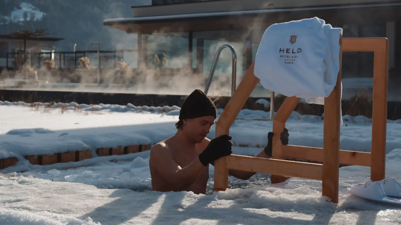 Mann im winterlichen Eisbad im Schnee mit Hotel Held Handtuch. Erfrischendes Wellness-Erlebnis im Sport- und Wellnesshotel Held****s.