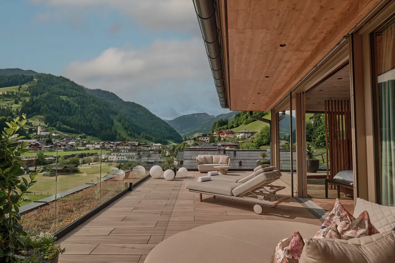 Geräumige Sonnenterrasse mit bequemen Liegen und Bergblick im DAS EDELWEISS Salzburg Mountain Resort.