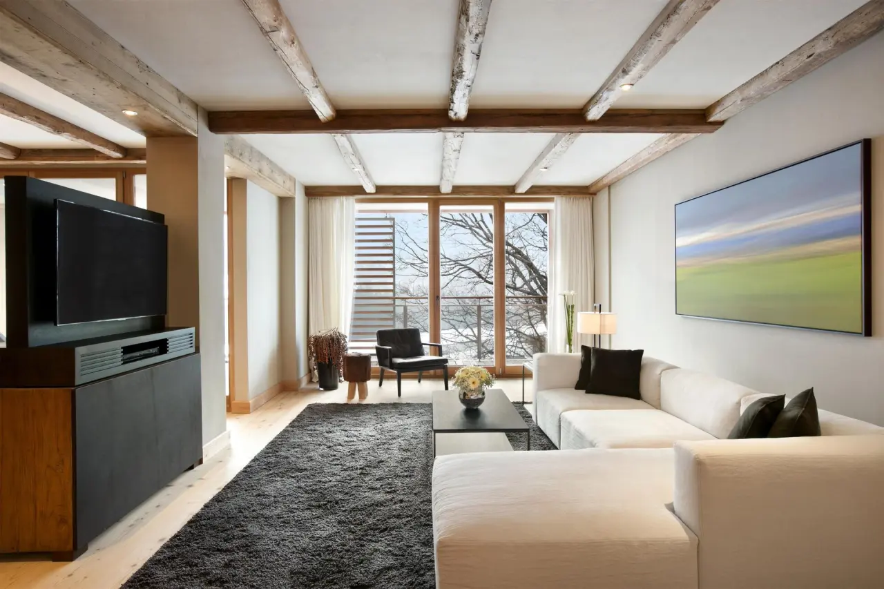 Luxuriöses Wohnzimmer einer Suite im Kempinski Hotel Das Tirol mit Holzbalken und Winterlandschaftsblick.