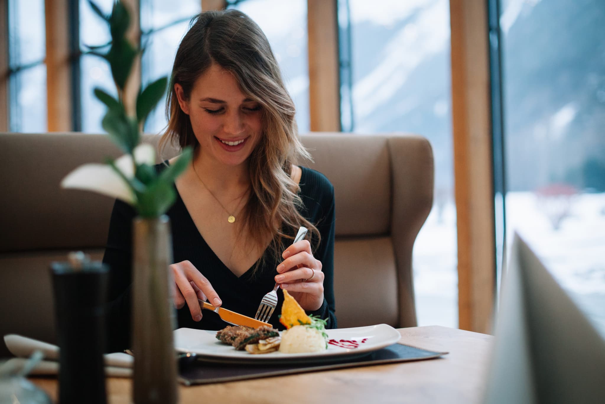 AQUA DOME in Längenfeld – Frau genießt eine Mahlzeit im Restaurant mit Bergblick | Wellnesshotel Tirol