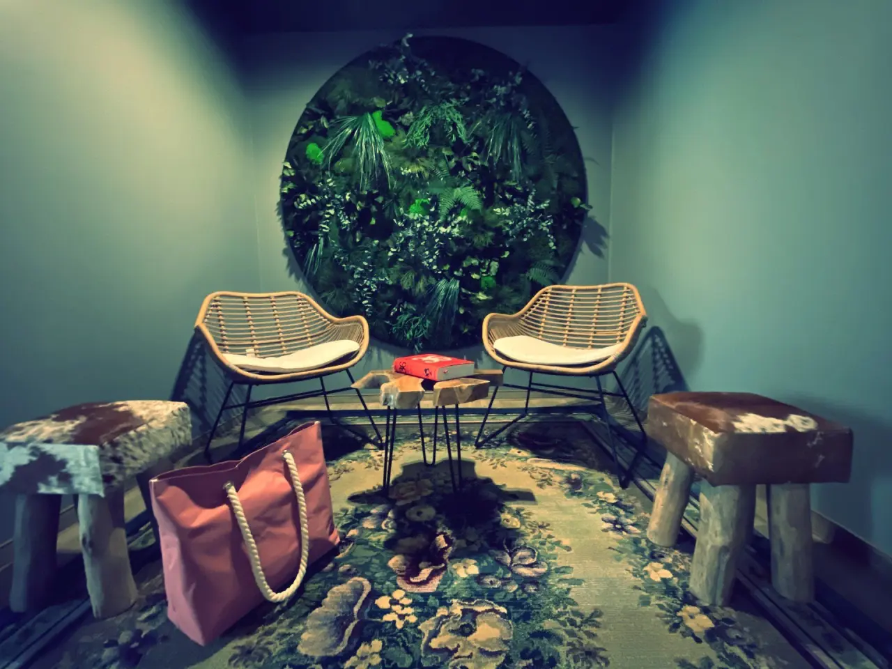 Dekorative Sitzecke mit Pflanzenwand, Rattansesseln und floralem Teppich im Hotel Seela.