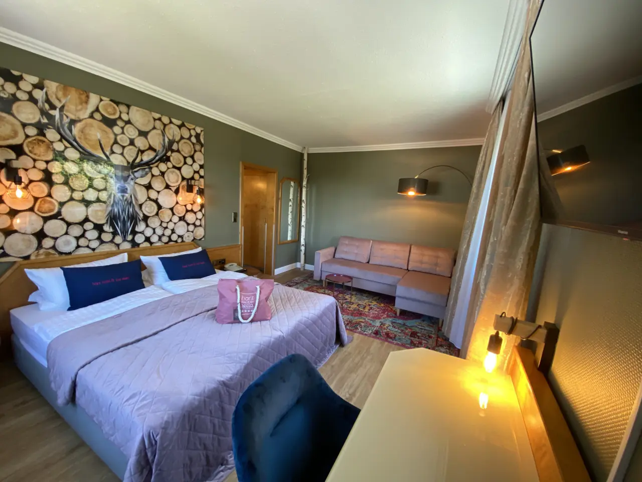 Gemütliches Doppelzimmer im Hotel Seela mit modernem Design, Hirschmotiv-Wandbild und bequemer Sitzecke für Ihren Aufenthalt.