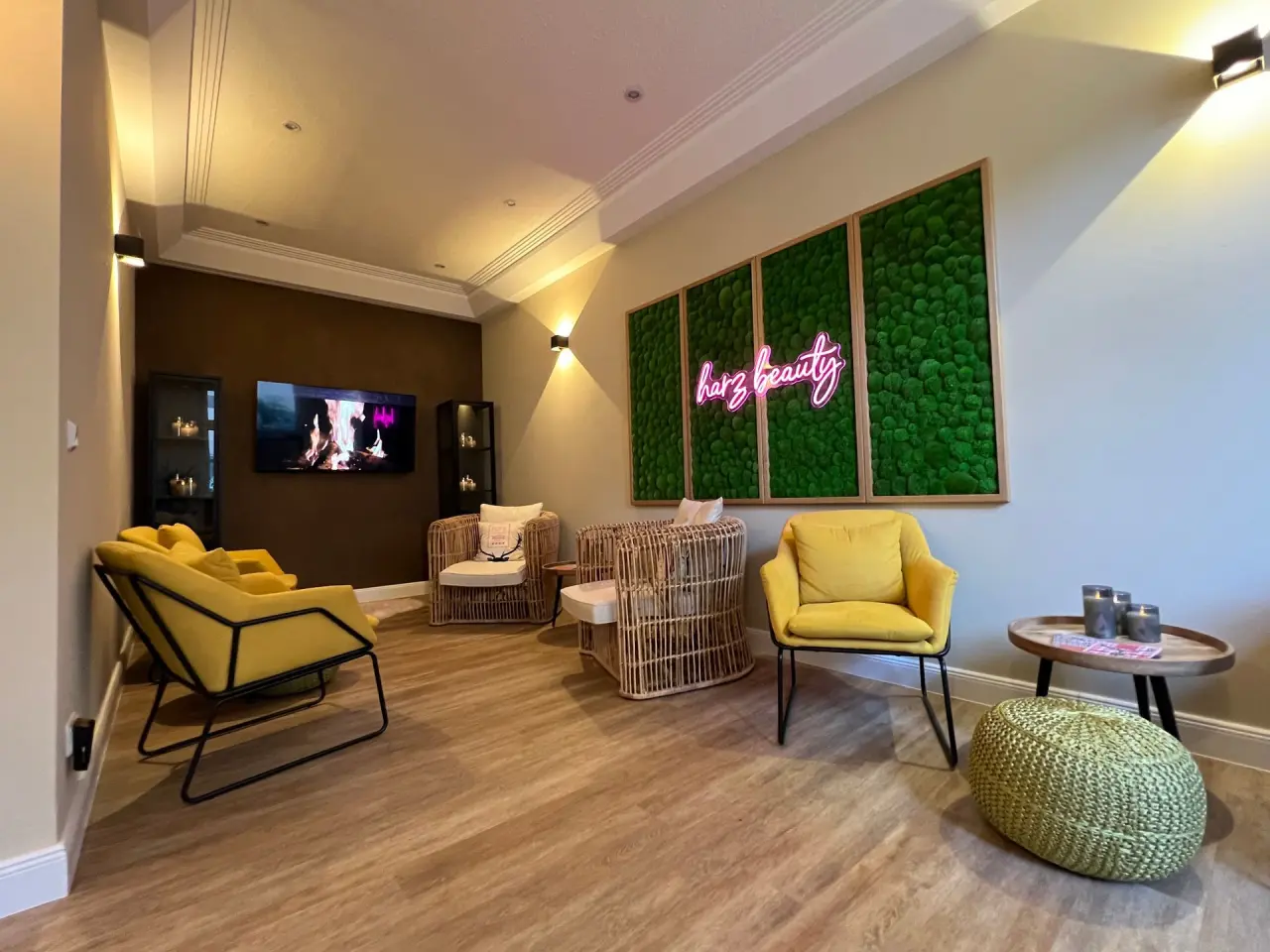 Moderne Lounge im Beauty-Bereich des Hotel Seela mit gelben Sesseln, Mooswand und Neon-Schriftzug 'harz beauty'.