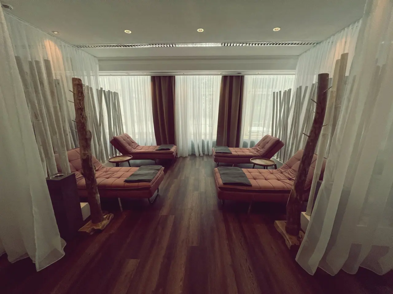Entspannungsbereich mit bequemen Liegen, Vorhängen und Holzelementen im Wellnessbereich des Hotel Seela.