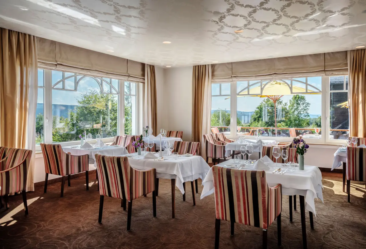 Helles Restaurant mit elegant gedeckten Tischen und Panoramablick ins Grüne im Hotel Waldhaus Ohlenbach.