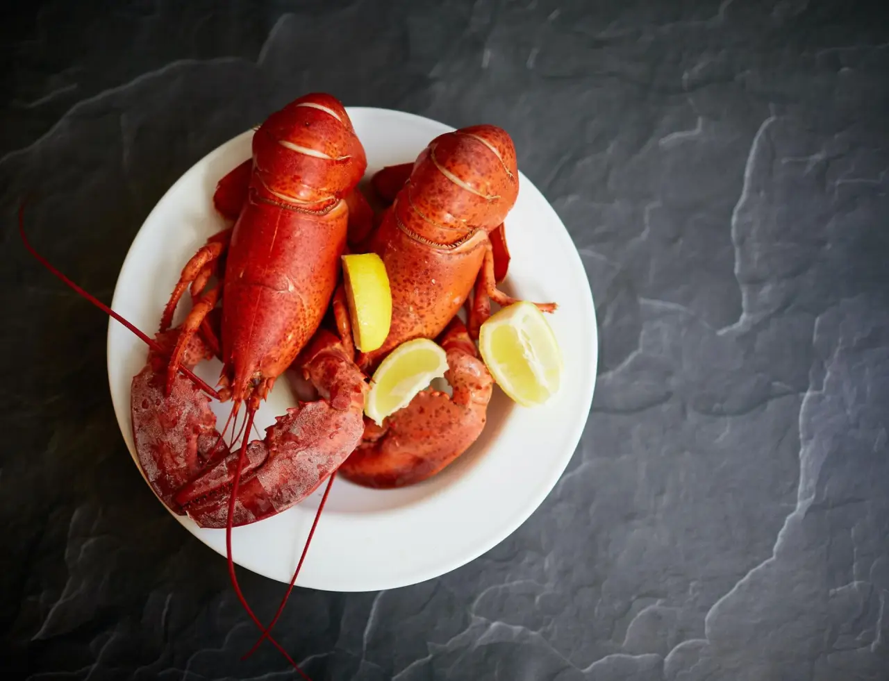 Zwei frische Hummer mit Zitronenspalten auf einem Teller im Restaurant des Waldhaus Ohlenbach.