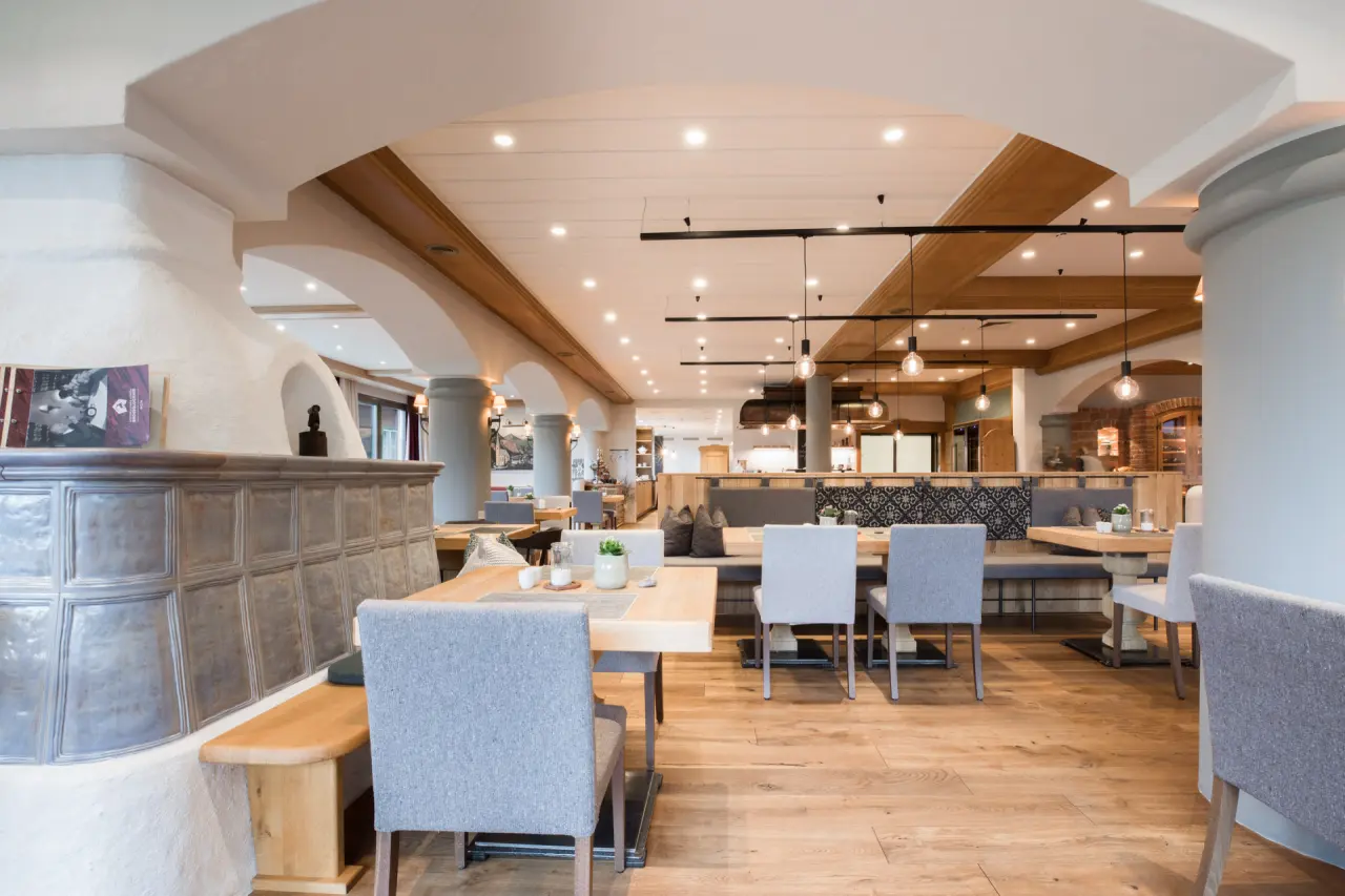 Gemütlicher Restaurantbereich mit Holzböden und Kachelofen in der Nationalpark Lodge Grossglockner