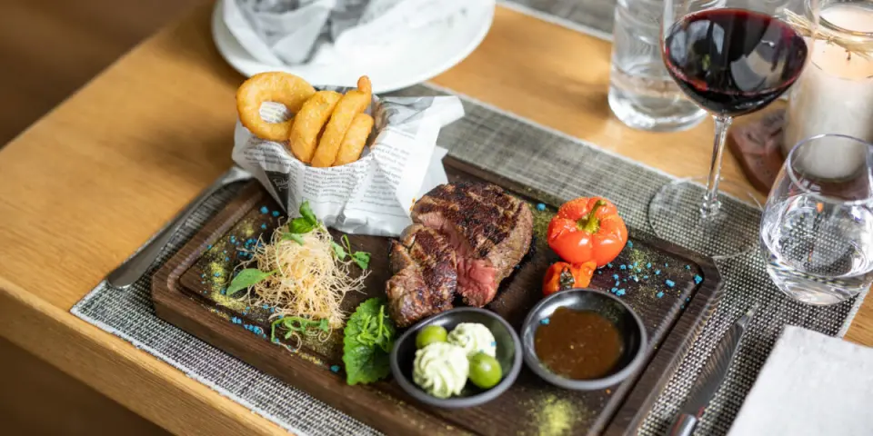 Saftiges Steak mit Beilagen und Rotwein im Restaurant der Nationalpark Lodge Grossglockner.