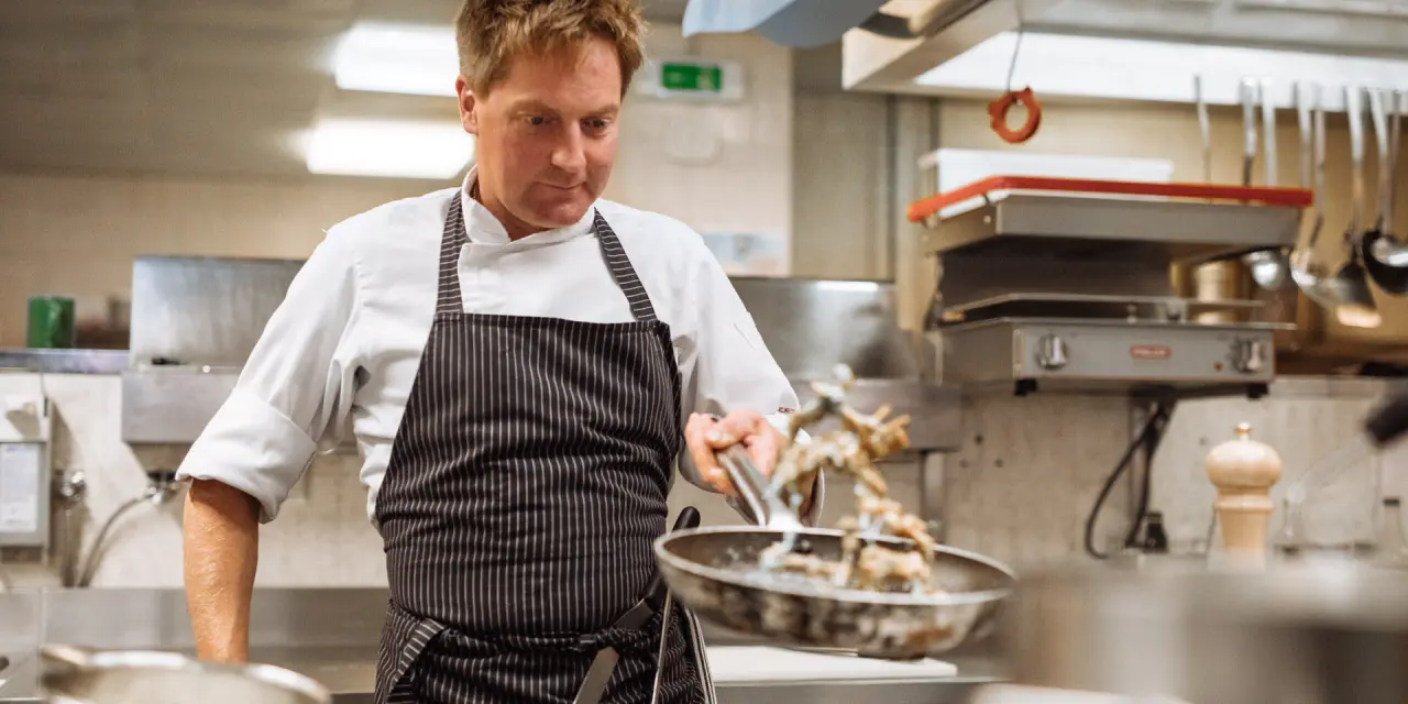 Koch bei der Zubereitung von Speisen in der Küche der Nationalpark Lodge Grossglockner