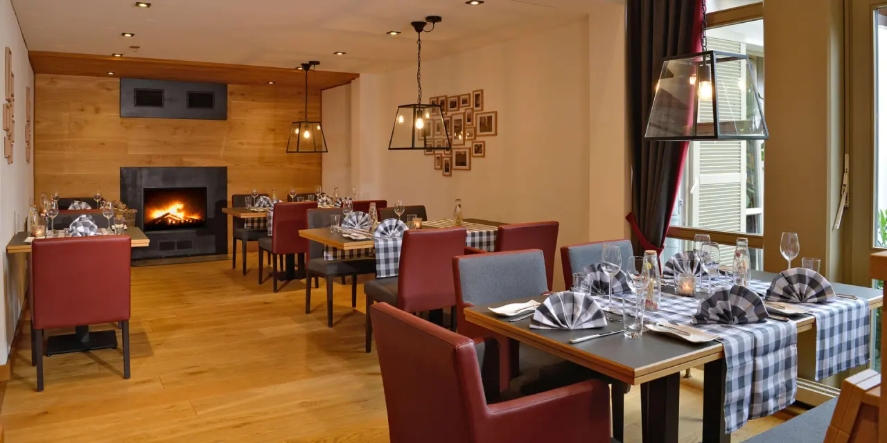 Gemütliches Restaurant im Landhotel Schnuck mit Kamin, Holzwänden und einladend gedeckten Tischen für entspannte Abende.