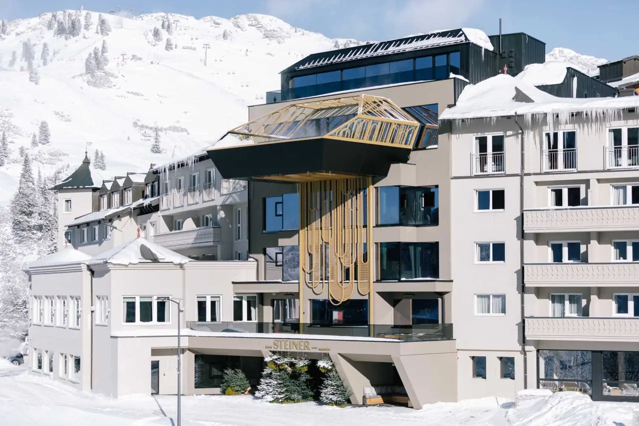 Modernes Hotel Steiner in verschneiter Berglandschaft mit Skiliften im Hintergrund. Ideal für Wellness- und Skiurlaub.